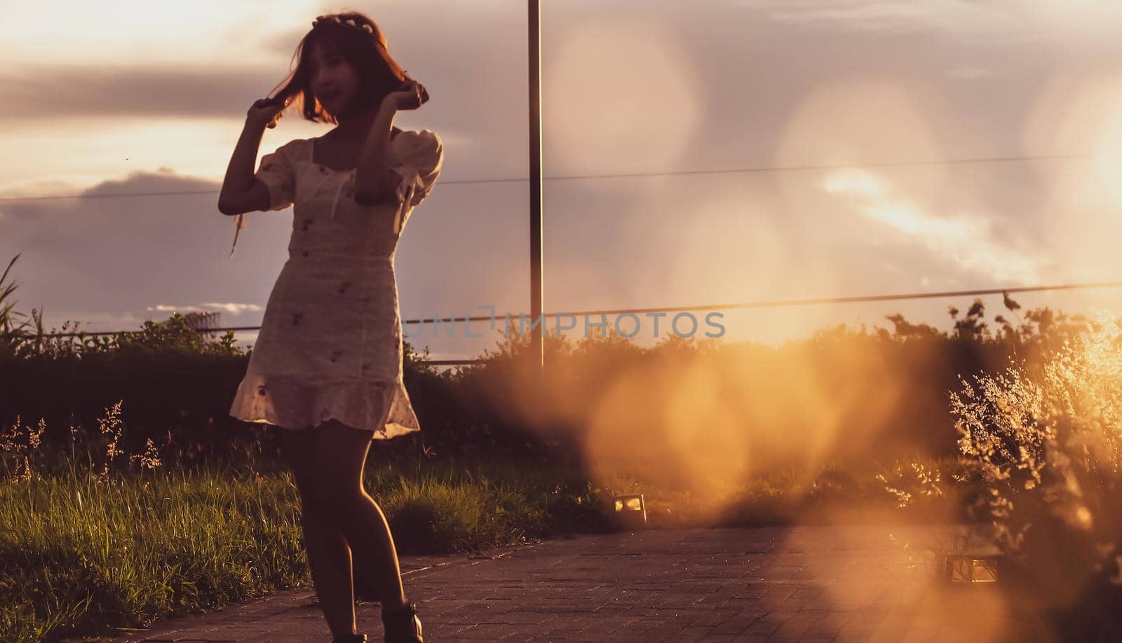 Silhouette of a young woman in a summer dress in a field wild flowers .sunlight in evening of summer in scene.