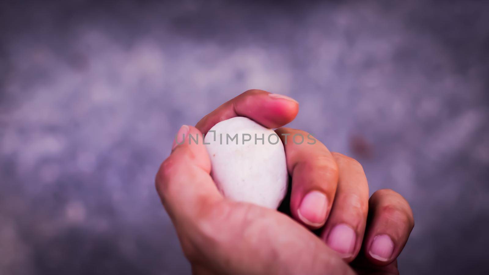 Stone held in hands. Hand hold stone ball in nature. Circular stone