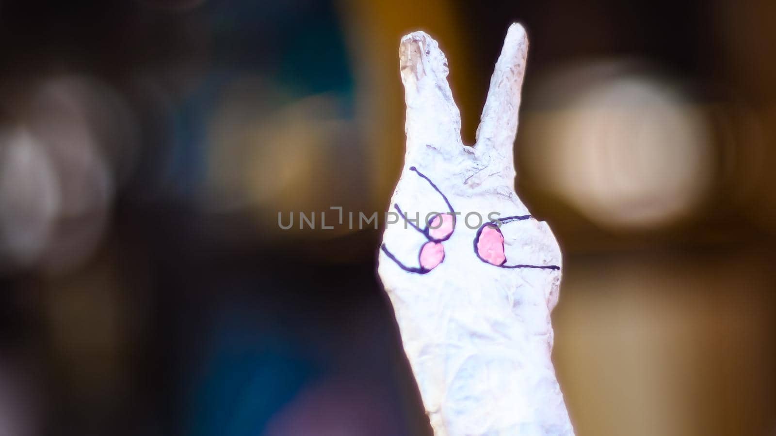 Hand showing peace gesture through torn yellow paper background. Victory, V sign. Two fingers victory peace sign body language