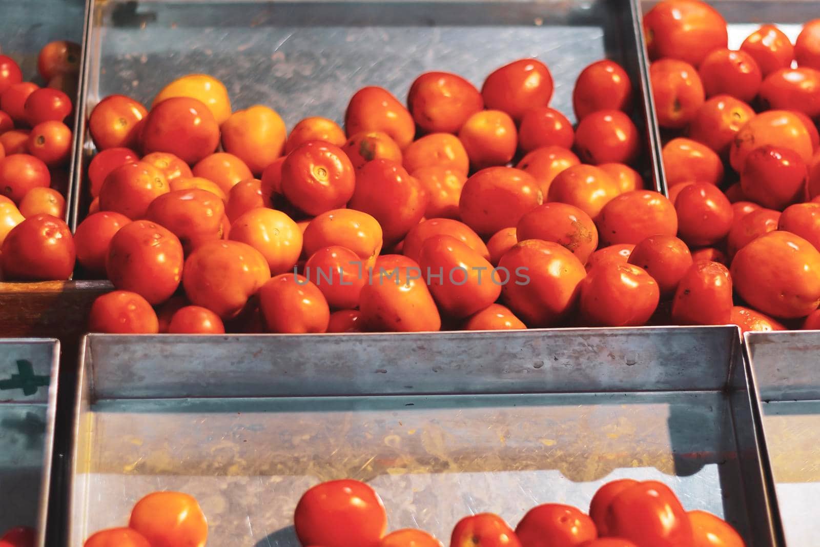 Red tomatoes in the metal boxes at the market. Healthy food idea.