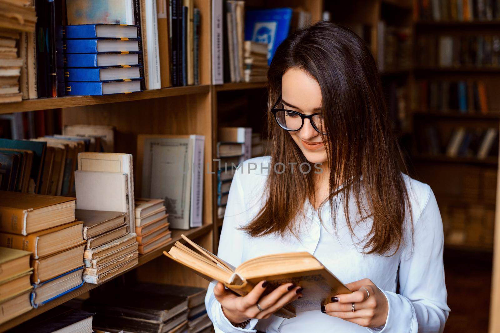 Young attractive university student reading a book in library