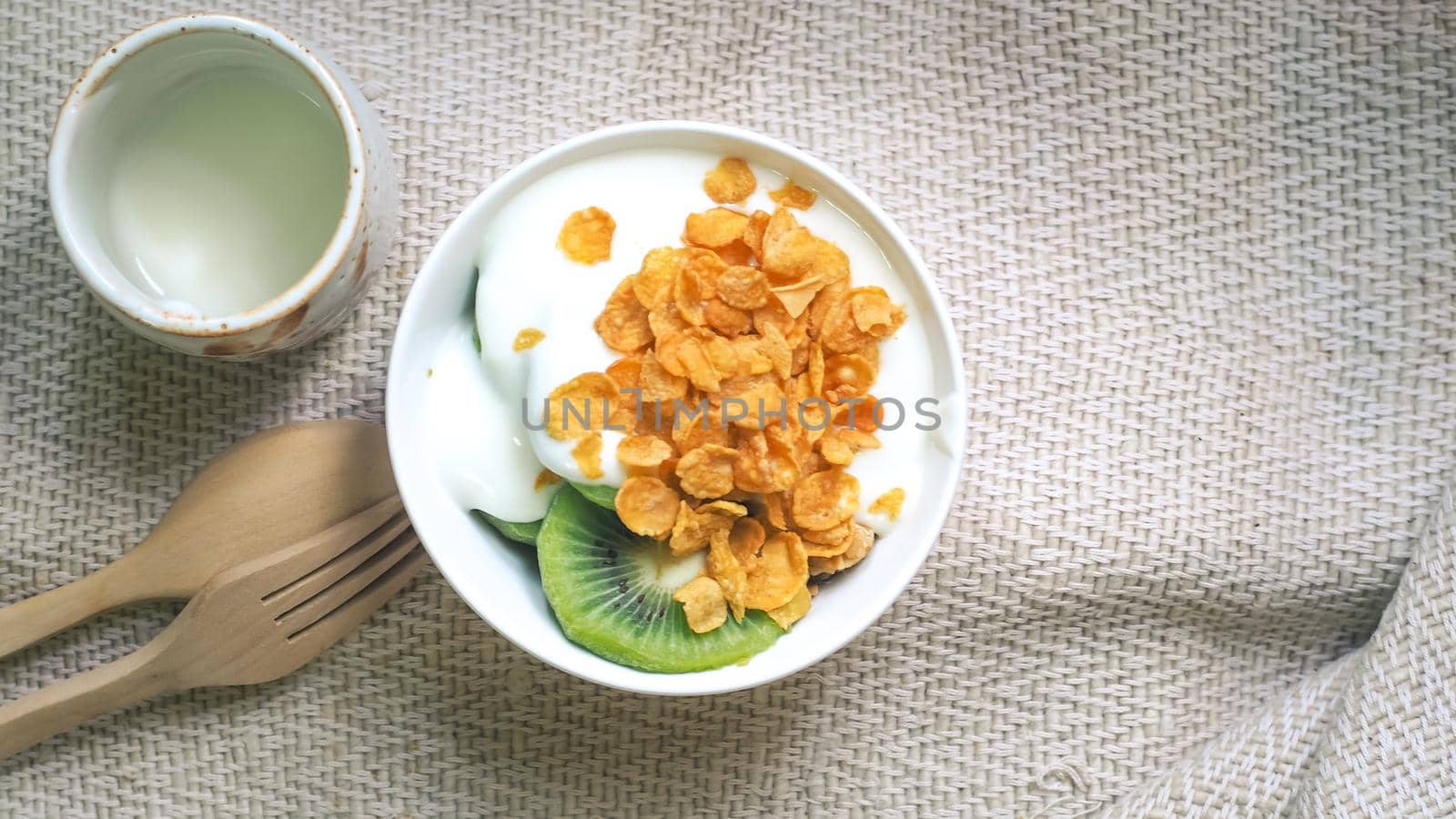 Corn flakes, cereal and milk splash in bowl. Natural homemade plain organic yogurt in wood bowl on wood texture background