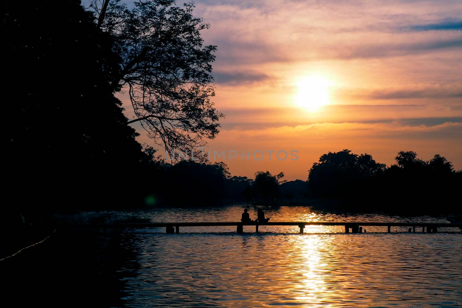 Sunset over the lake .silhouette photography. Romantic moment. Couple on the bridge