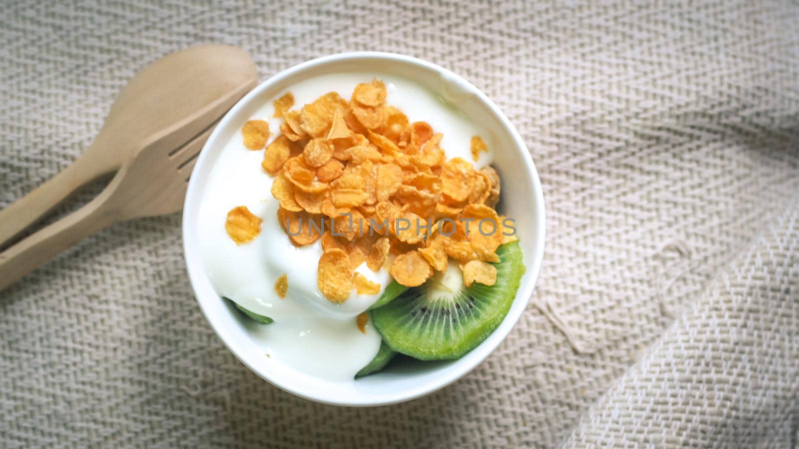 Corn flakes, cereal and milk splash in bowl. Natural homemade plain organic yogurt in wood bowl on wood texture background by Petrichor