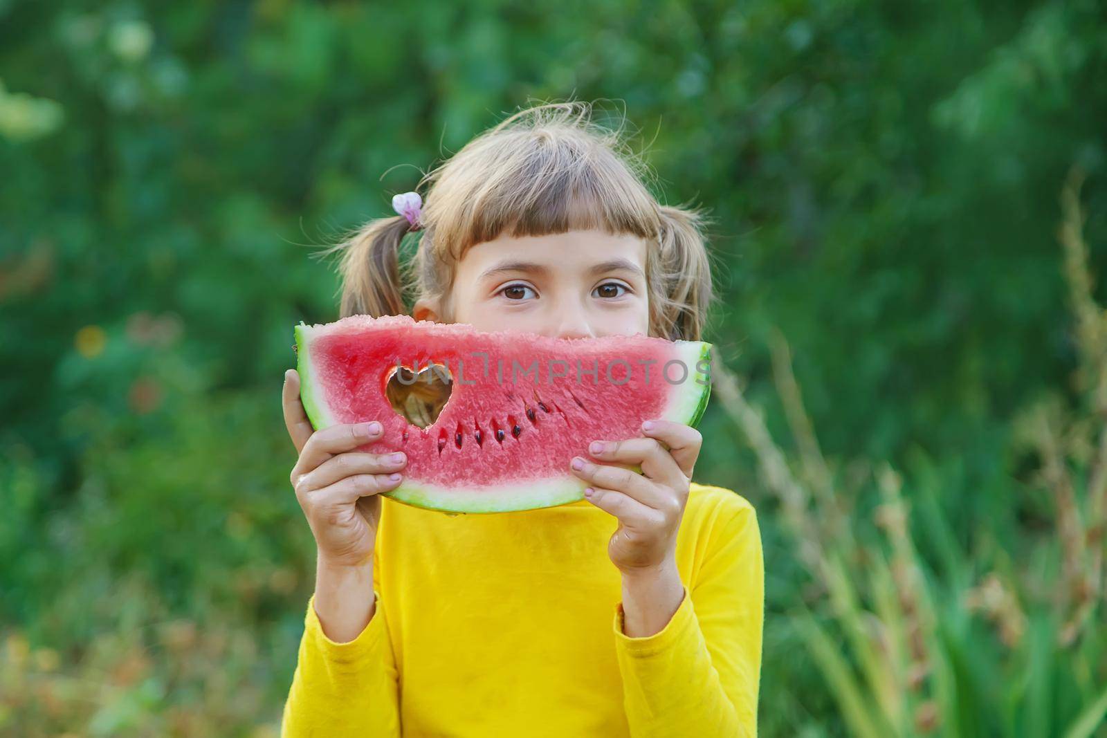 child eats a watermelon in the garden. Selective focus. by yanadjana