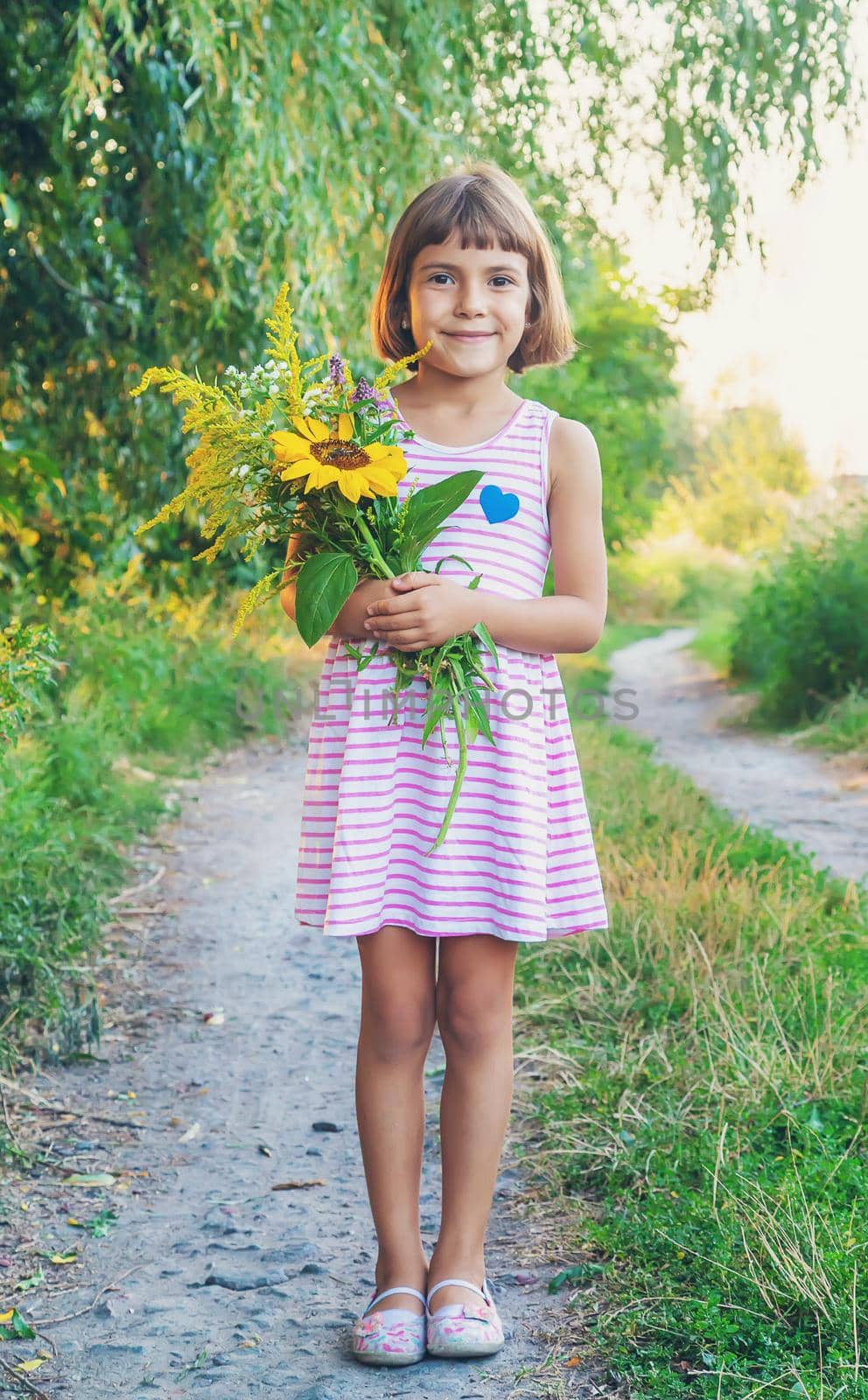 child holds a bouquet of wildflowers in his hands. Selective focus. by yanadjana