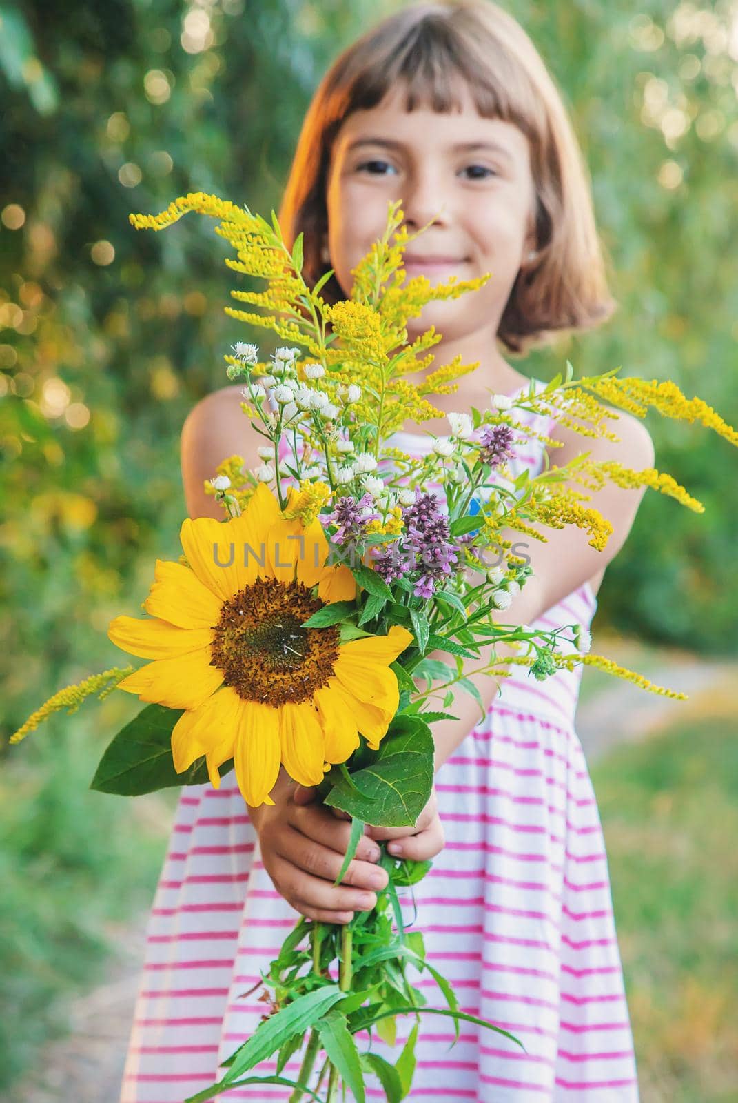 child holds a bouquet of wildflowers in his hands. Selective focus.