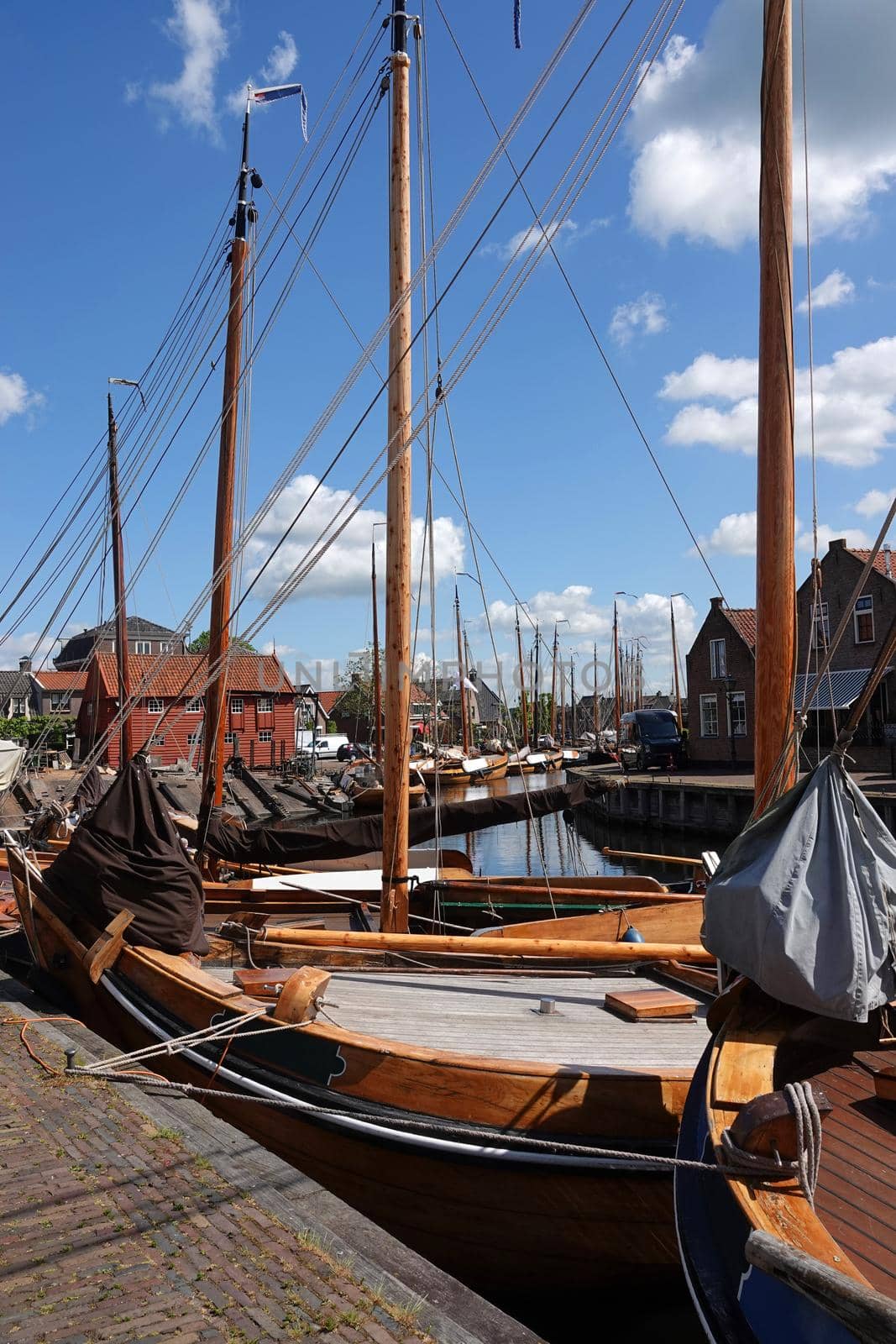 Old historical wooden fishing boats moored behind each other.  These are traditional Dutch botter boats. It's a bright sunny day in Bunschoten-Spakenburg, the Netherlands. This town was in the past an important fisher harbor when the inland sea IJsselmeer was still direct connected with the North sea.