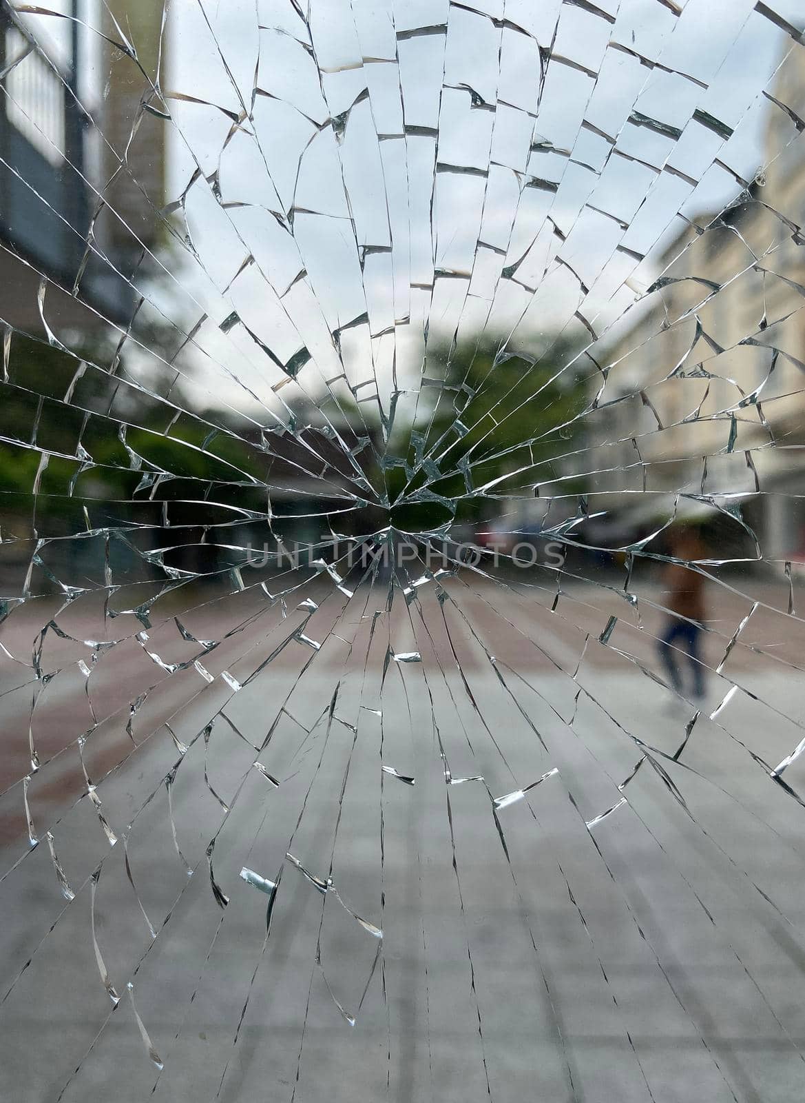 A street with a pedestrian seen through a broken window. Probably a case of vandalism.