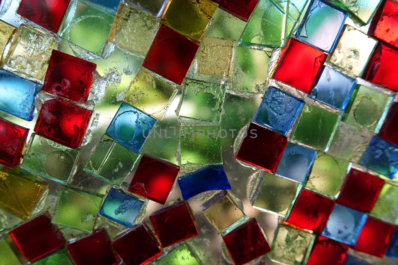 Colorful square glass mosaic stones glued on a glass plate. Meant as background