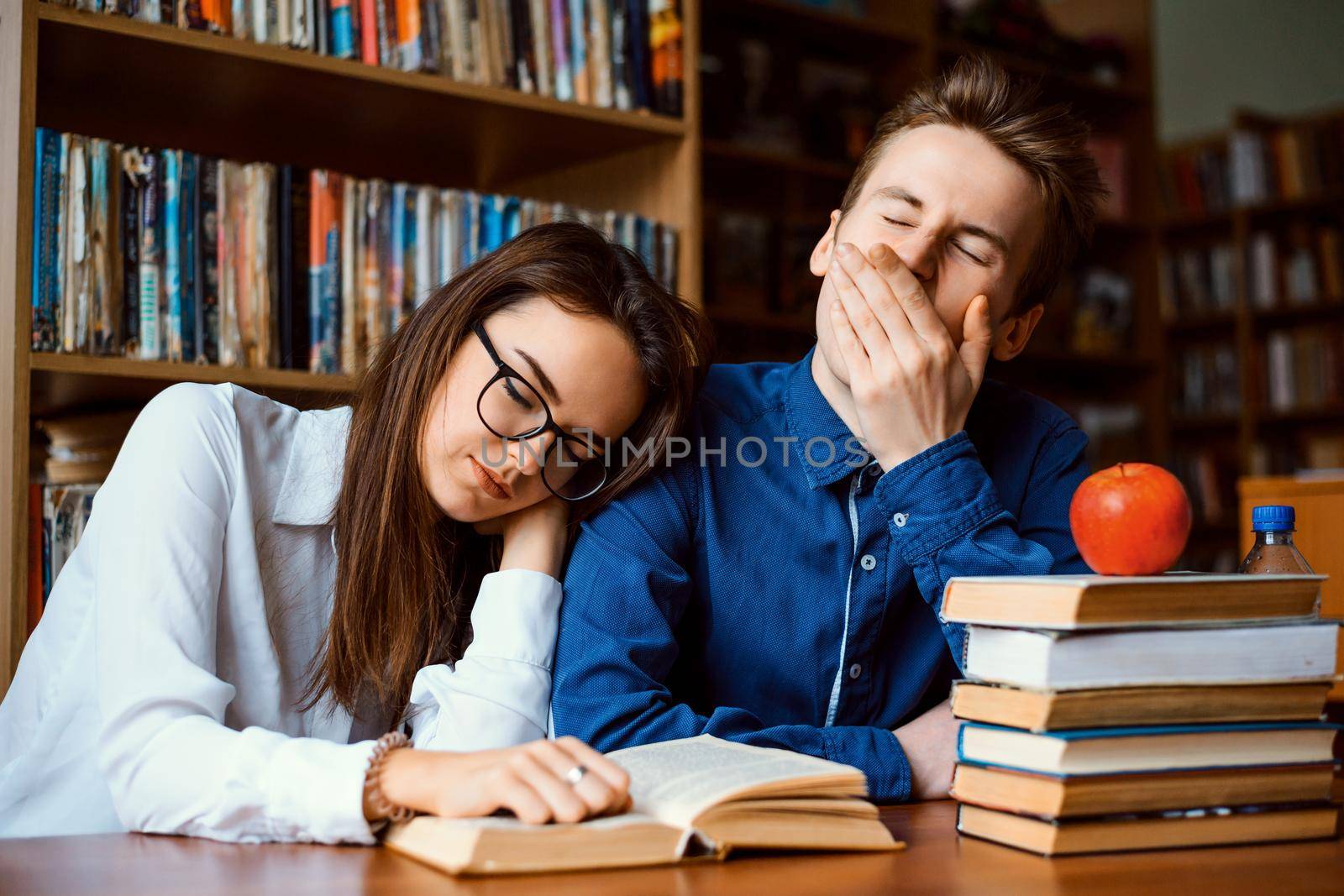 Bored students tired of constant studying fell asleep while working on project whole day and reading books in the library