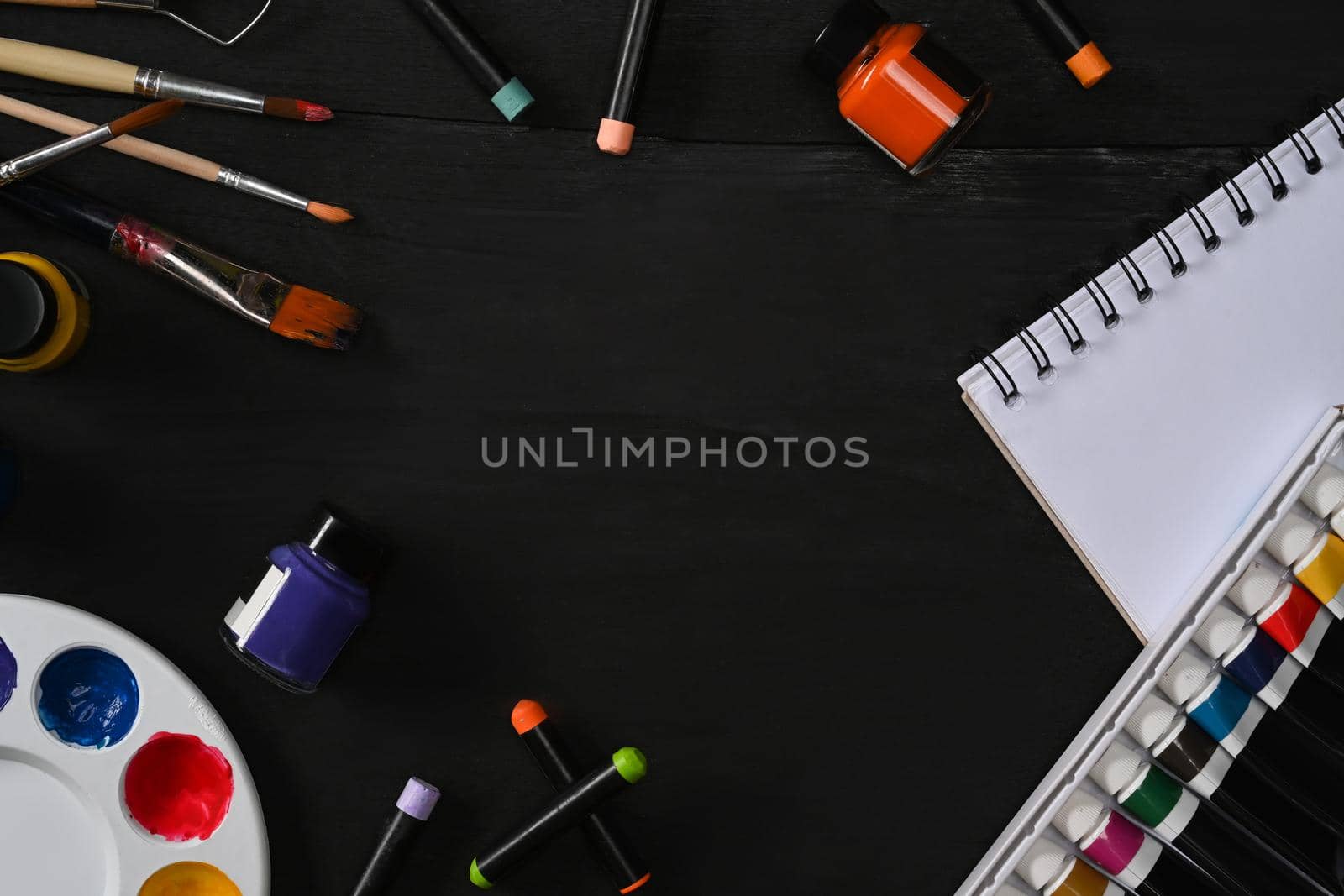 Artist workspace with sketchbook paint brushes, tube paint, watercolor and palette on blank wooden table. Art, workshop, painting, creativity concept by prathanchorruangsak