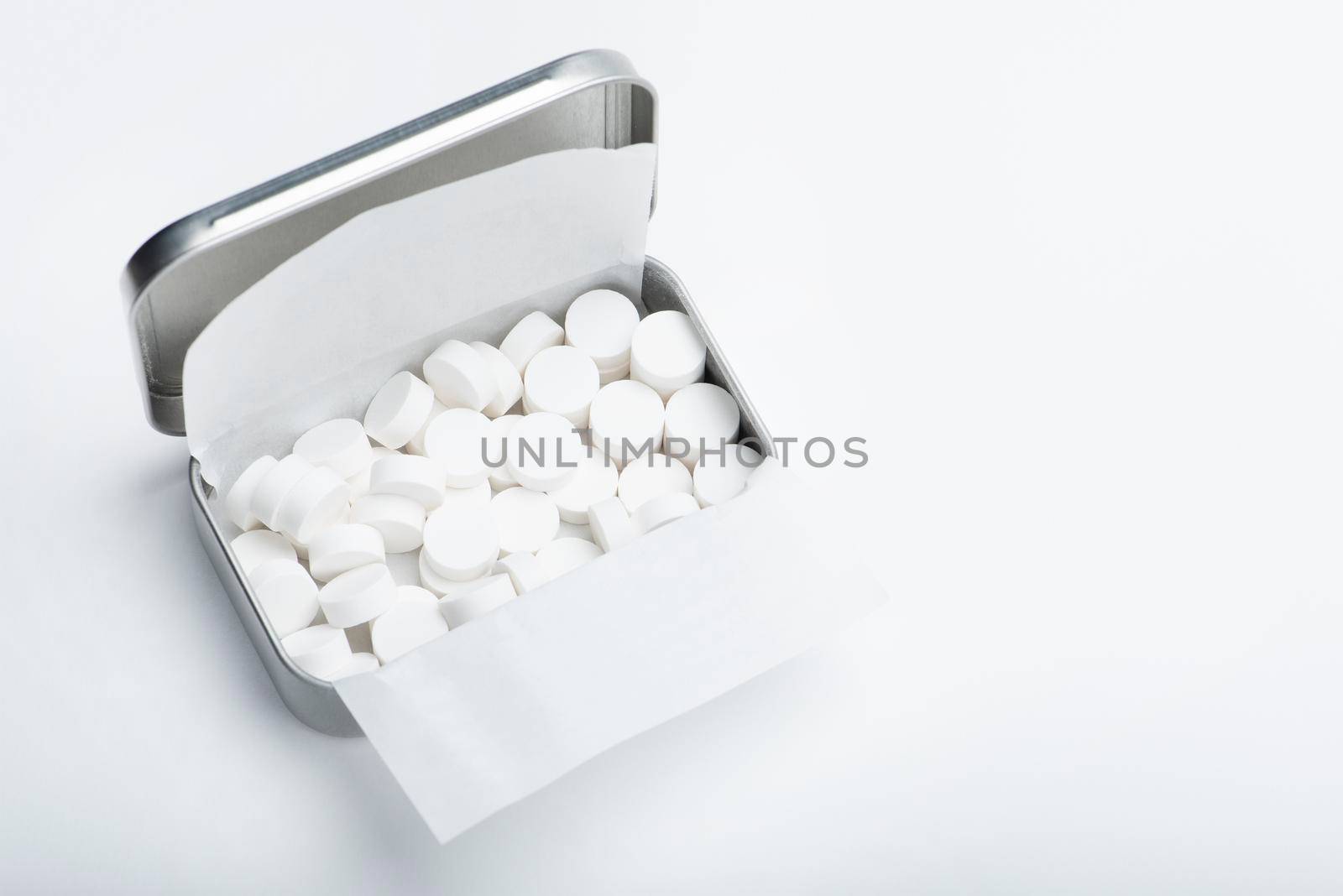 Mint candies on a white background. White mint candies in an open tin box. Fresh breath or bad breath concept.