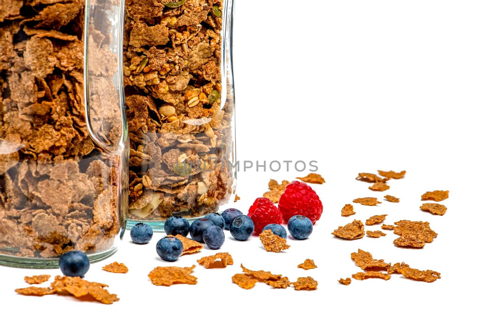 Isolate muesli. Dry muesli flakes with raspberries and blueberries lie on an isolated white background. Breakfast cereals in a glass jar on a white background