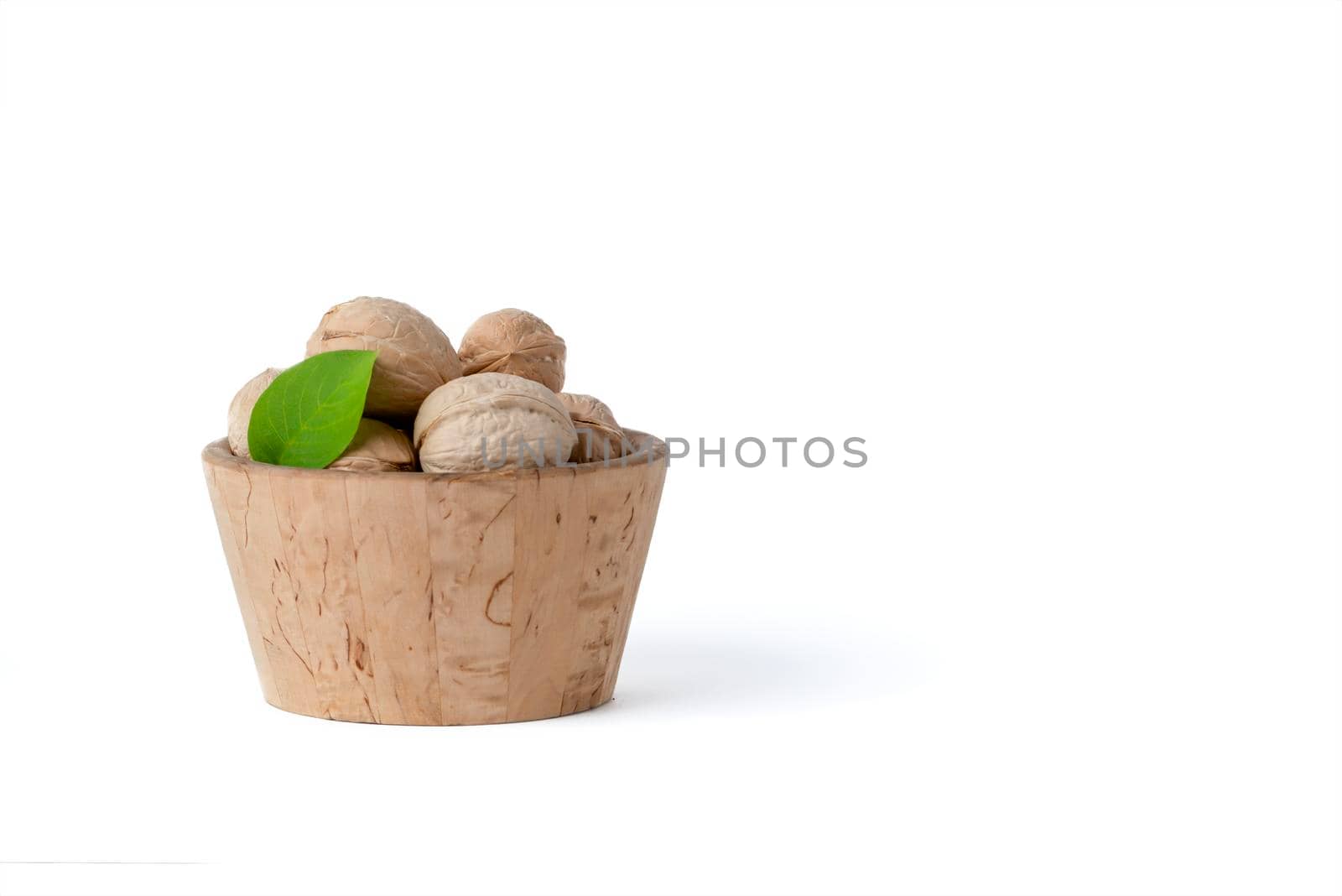 Walnut. Walnut fruits of different varieties lie in wooden saucers and baskets on a white isolated background. Nearby are green leaves and unripe walnut fruits