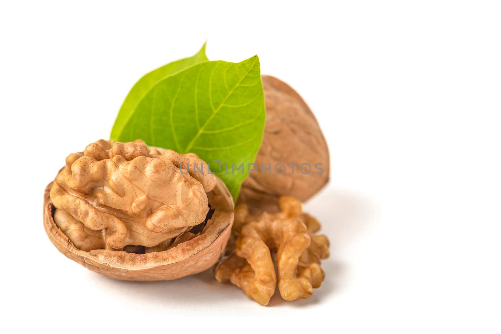 Peeled walnut fruits lie on a white isolated background with green leaves. Walnut in shell. White isolate for design and insertion into the project
