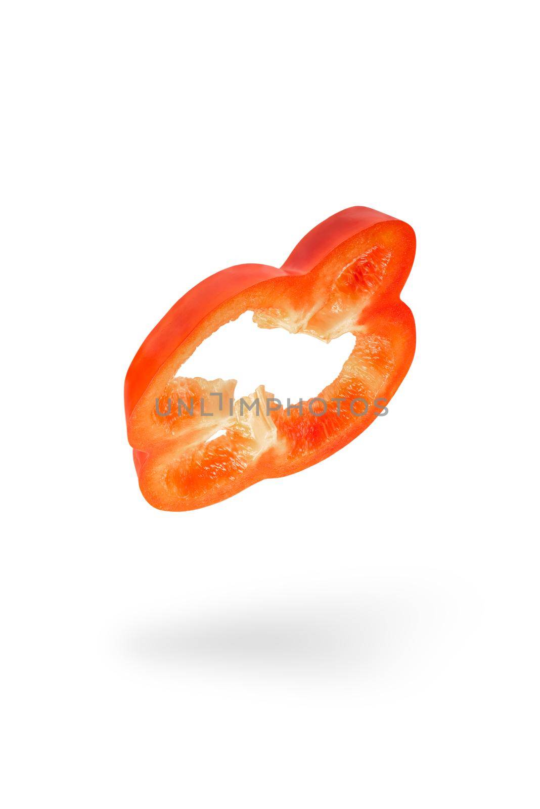 A slice of red paprika falls on a white backdrop. Red bell pepper flying in air on isolated white background by SERSOL