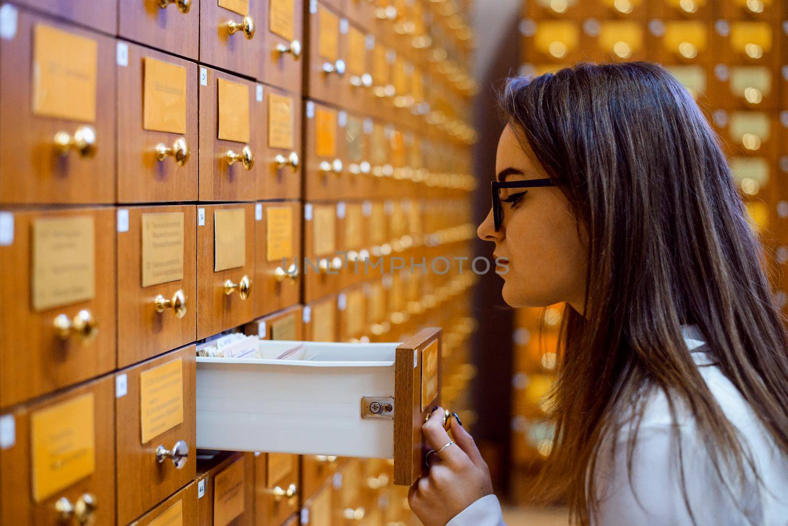 Library or archive reference card catalog. Student girl trying to find necessary book using library paper database