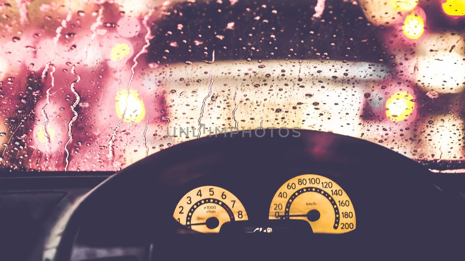 Interior of car when rains. Defocused blur of light on the road in a raining day by Petrichor