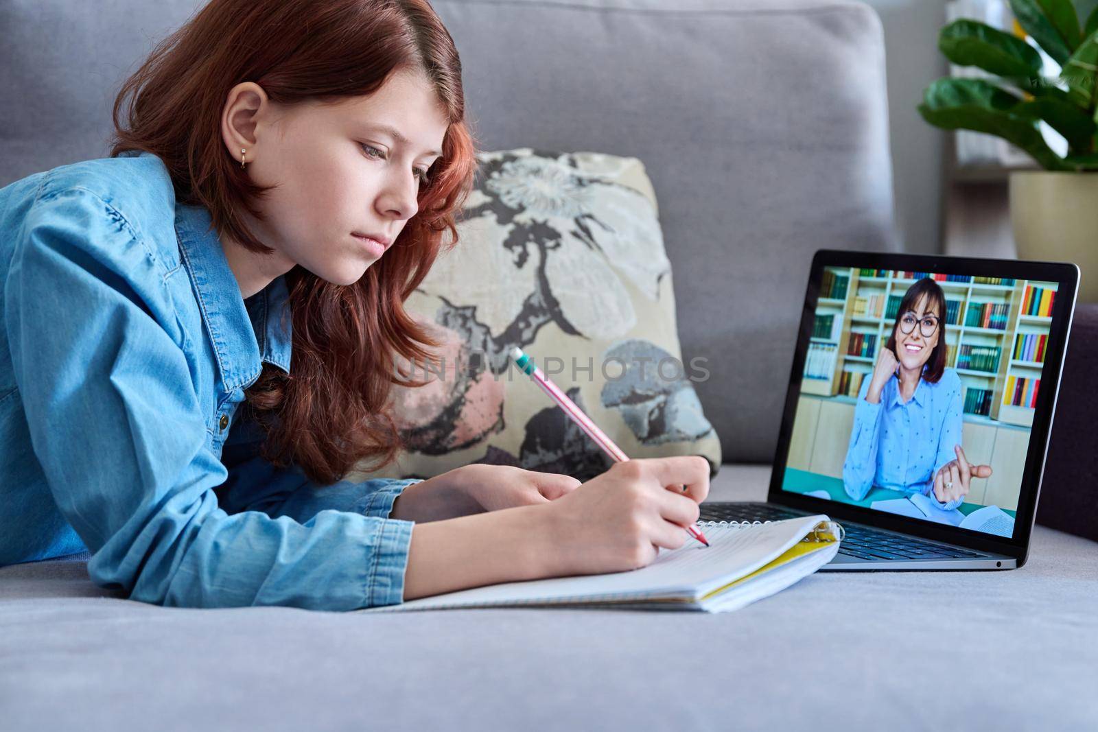 Preteen girl studying at home using laptop by VH-studio