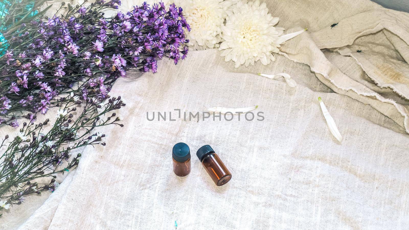 Bottle of essential oil. Herbal medicine or aromatherapy dropper bottle isolated on white background. Fresh rosemary flowers and essential oils on the table