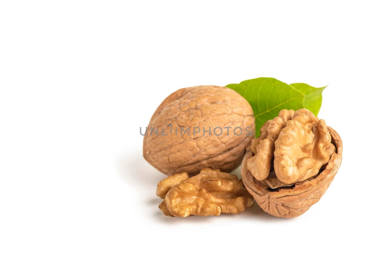 Peeled walnut fruits lie on a white isolated background with green leaves. Walnut in shell. White isolate for design and insertion into the project