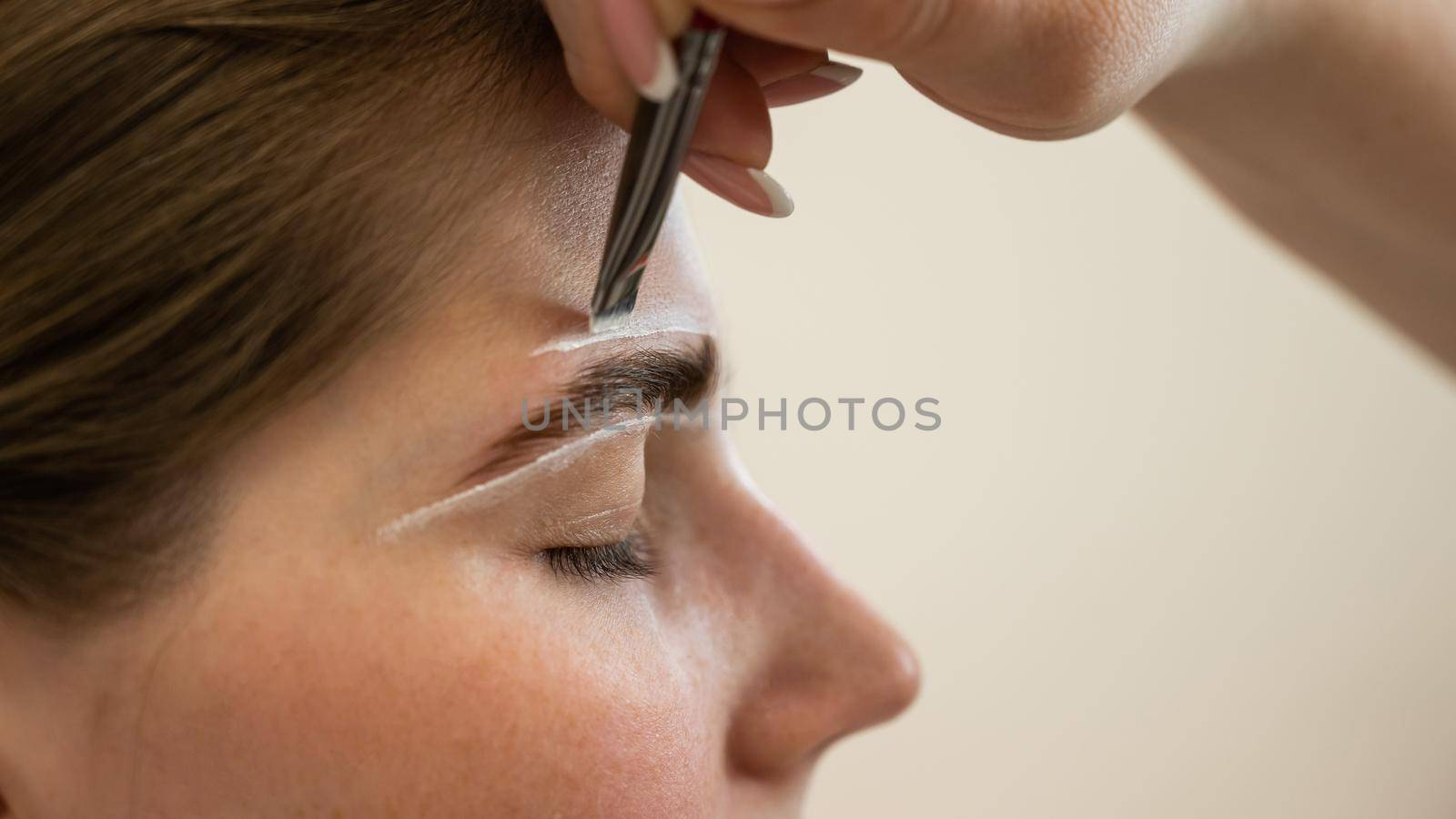 The master draws the shape of the eyebrows with white paint before coloring