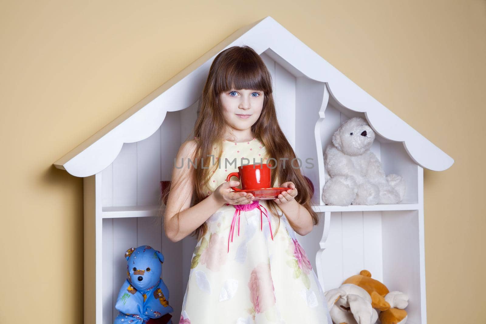 Happy little girl with cup of tea in her room. drinking and happy. studio shot.