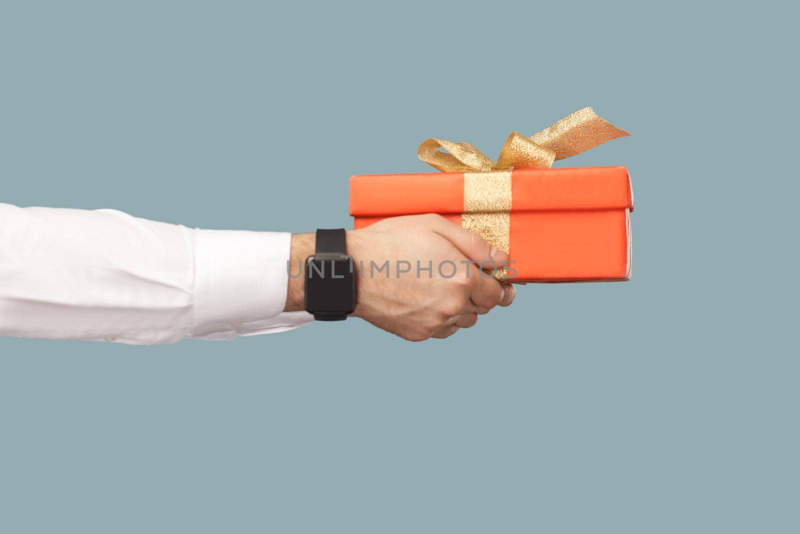 human hand in white shirt with black smart watches holding red gift box with gold ribbon. by Khosro1