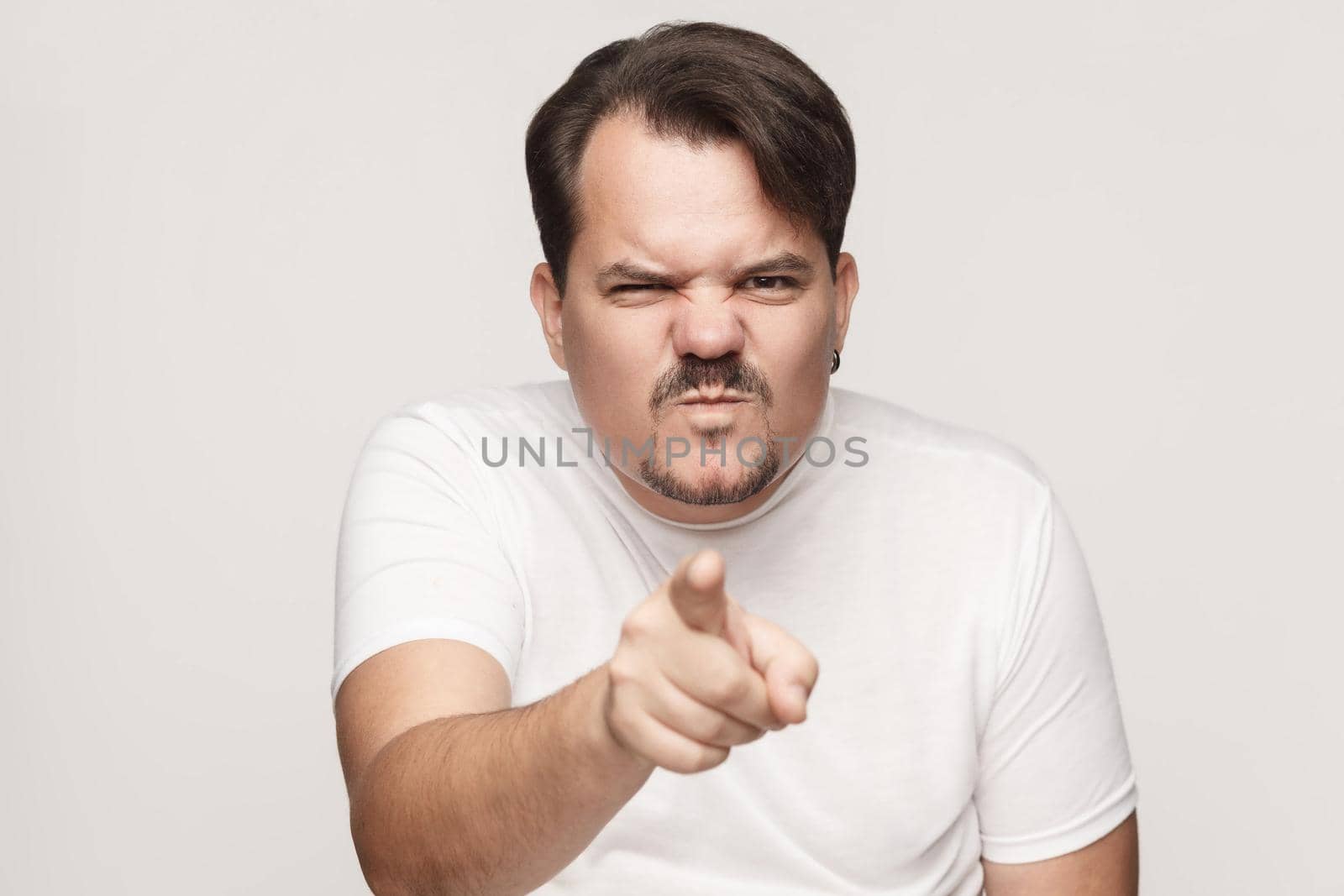 Anger adult man pointing finger at camera. Studio shot, isolated on gray background