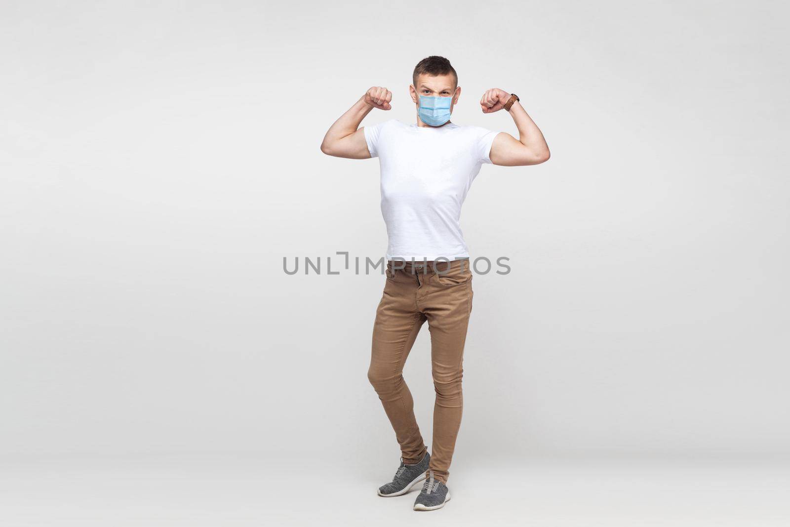 man with surgical medical mask standing and showing his biceps and looking with haughty face. by Khosro1