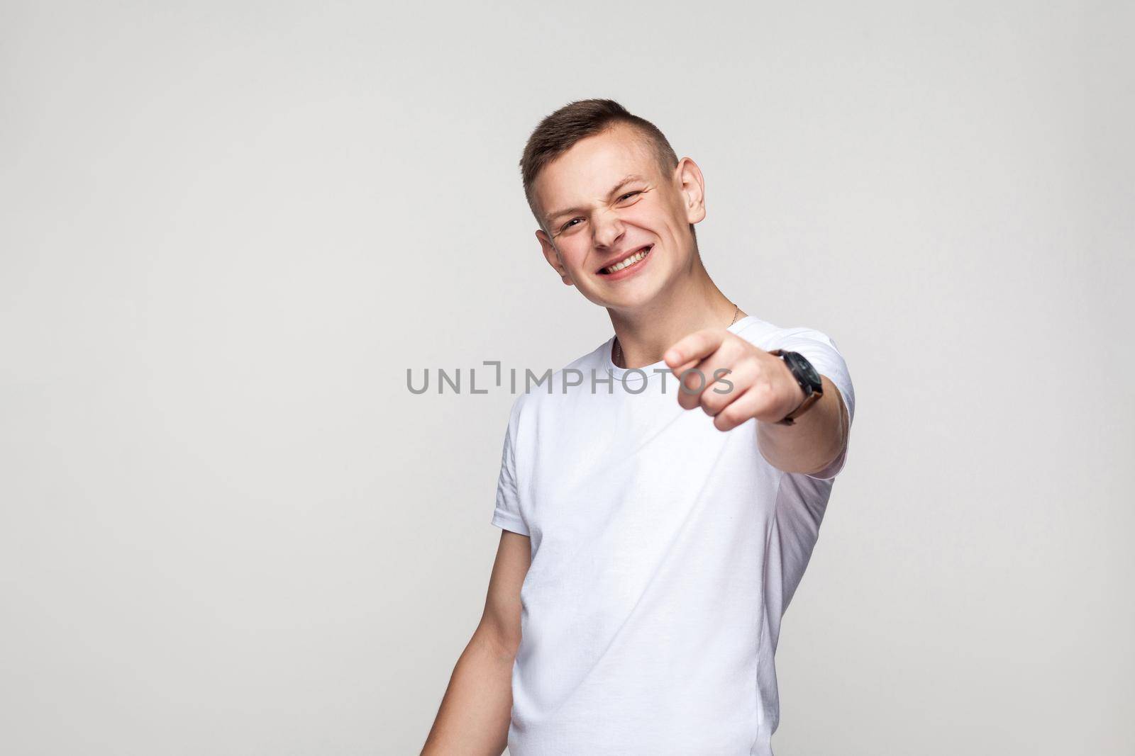 Happiness young boy pointing finger at camera and toothy smiling. Studio shot