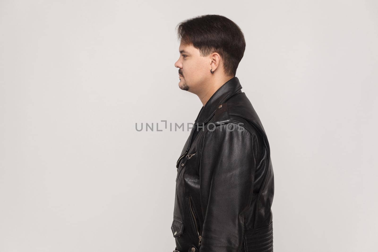 Profile neformal man in leather jacket. Indoor shot in gray background