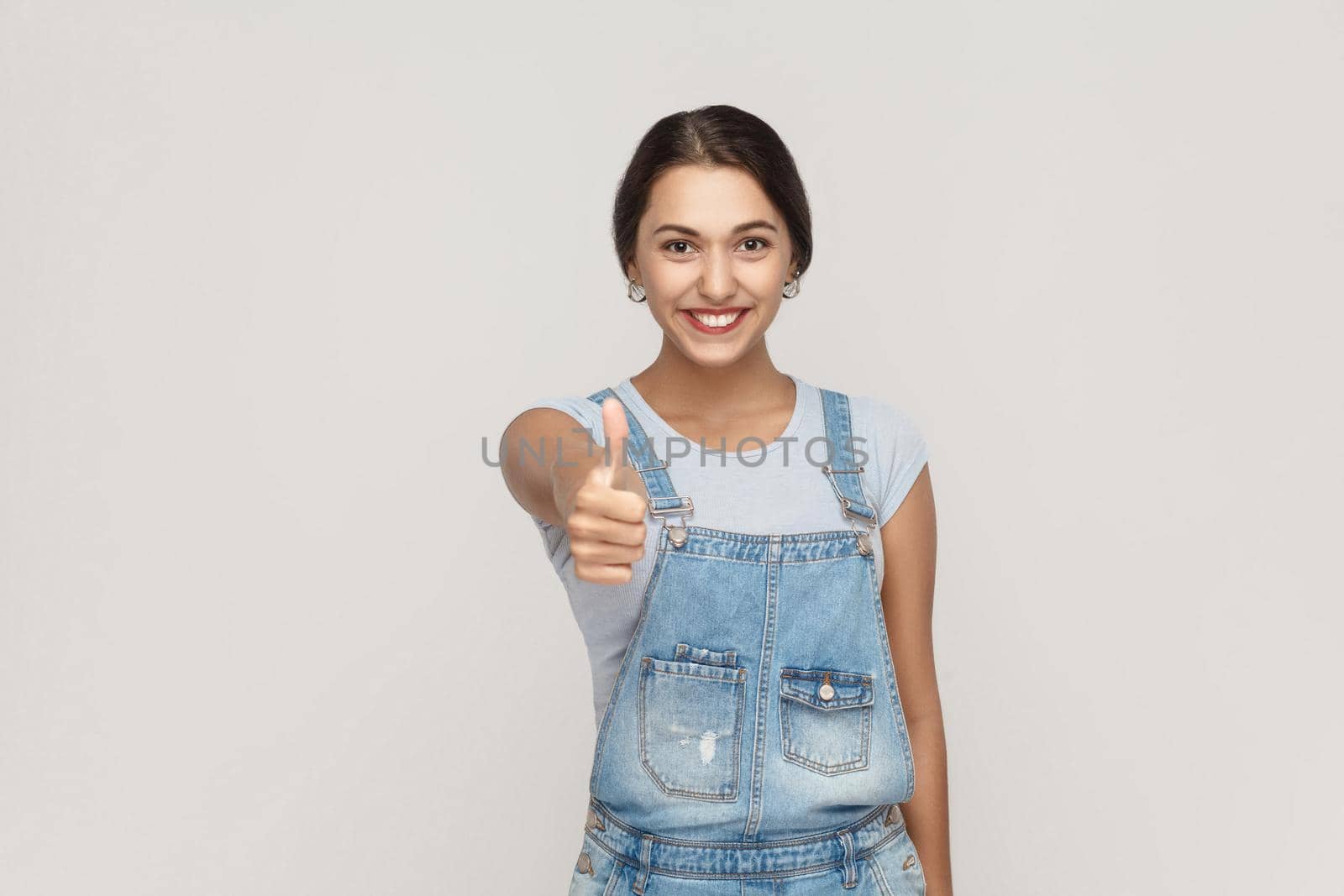 The young cheerful mixed race woman showing thumb up and toothy smile and looking at camera. by Khosro1