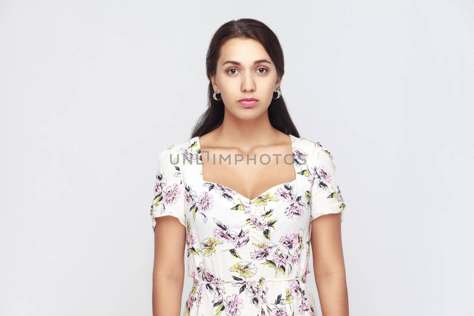 Seriously latin woman looking at camera. Studio shot, isolated on gray background