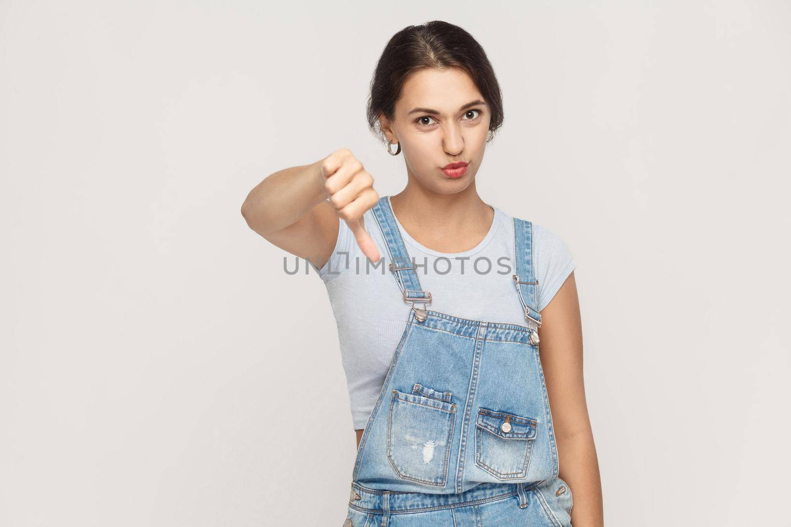 Young adult woman showing thumb down isolated on a gray background. Studio shot.