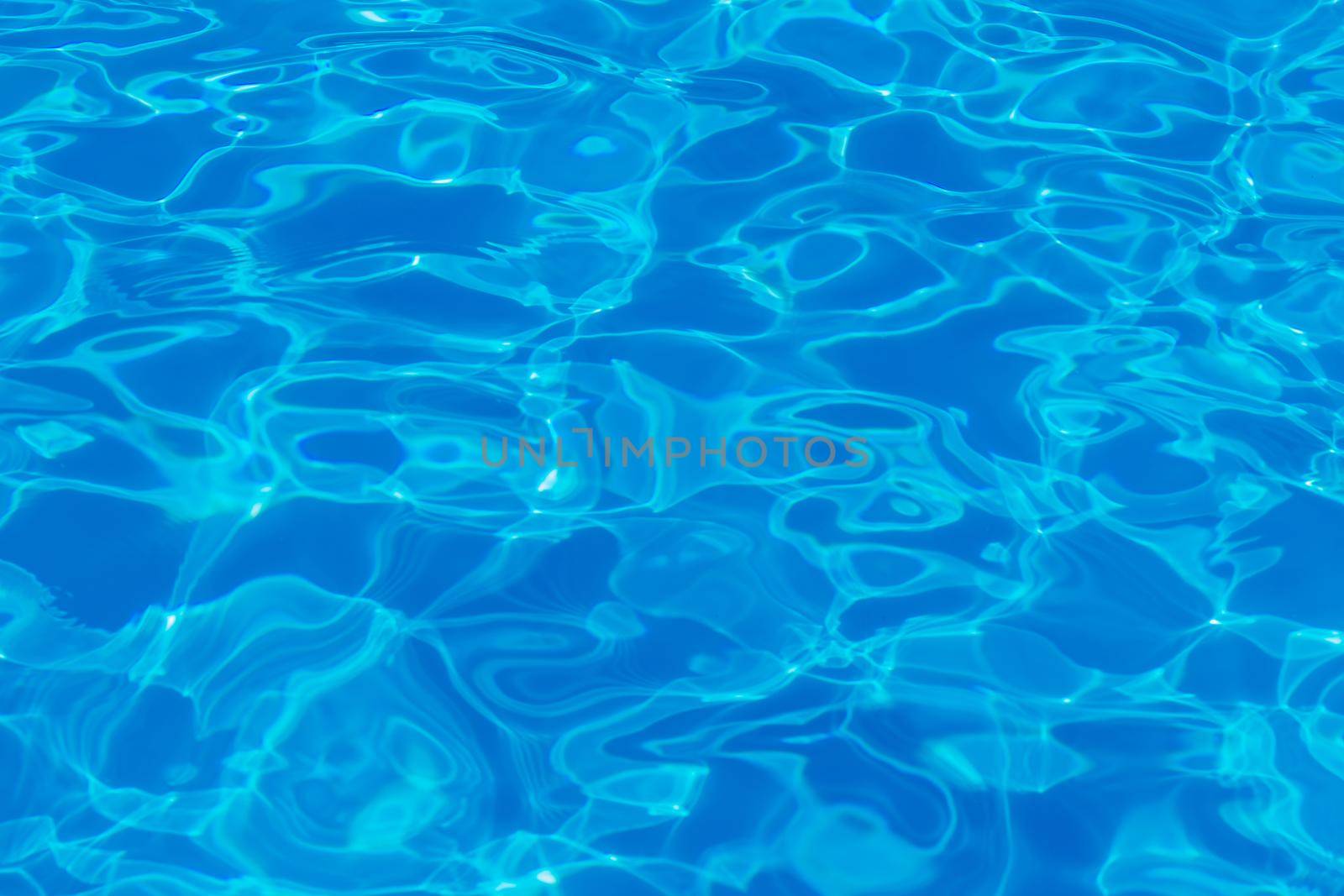 Swimming pool water surface with sparkling light reflections. Aqua background.