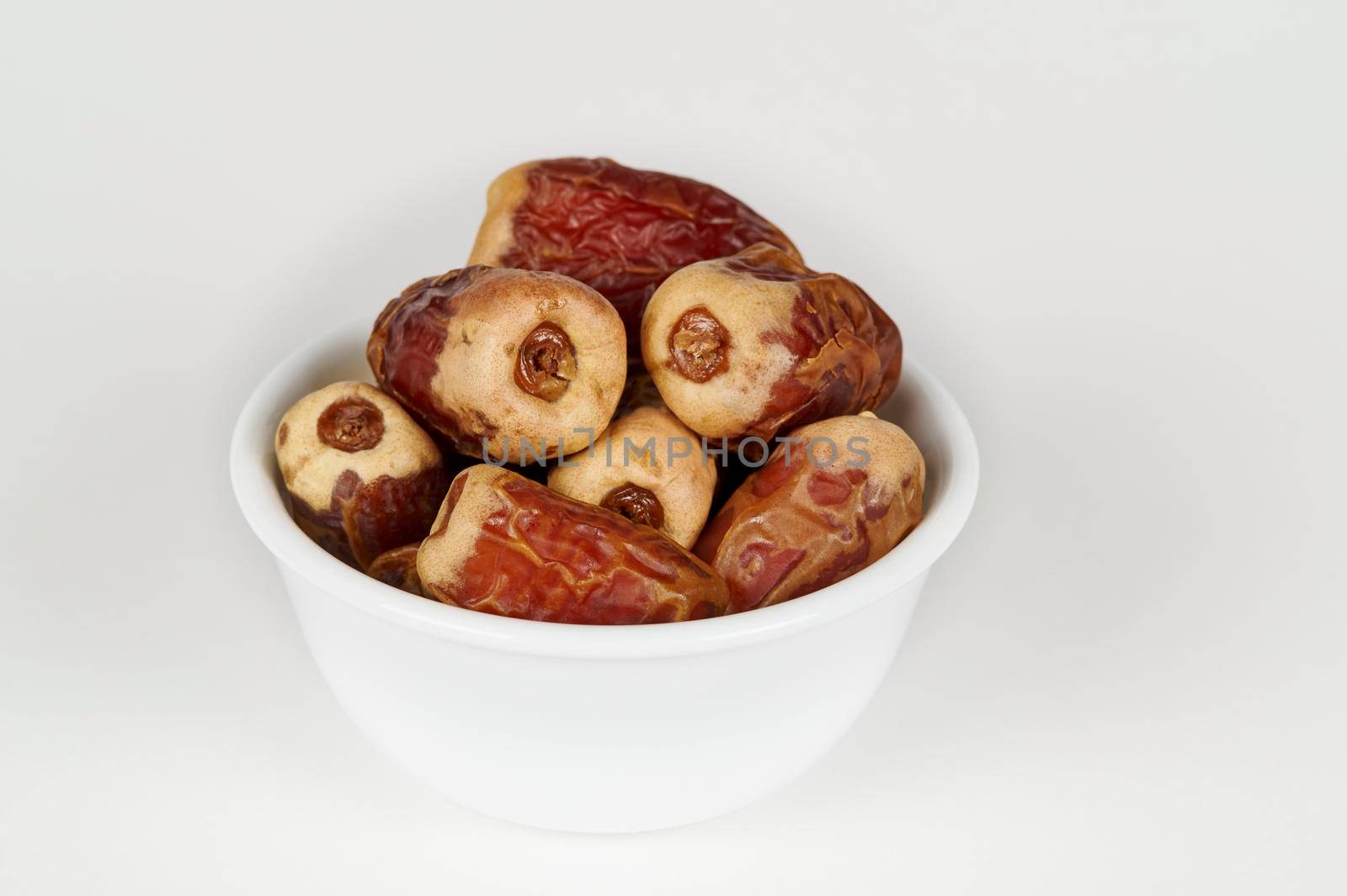 Closeup view of a bowl of Sagai dates on a white background