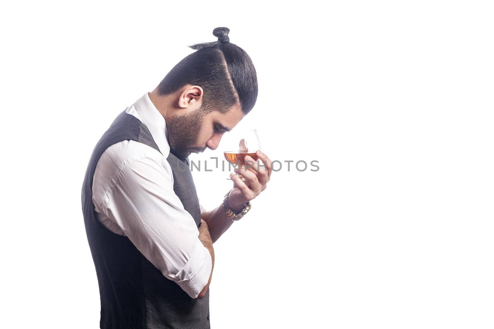 Handsome bearded businessman holding a glass of whiskey. side view, holding glass and thinking. studio shot, isolated on white background.