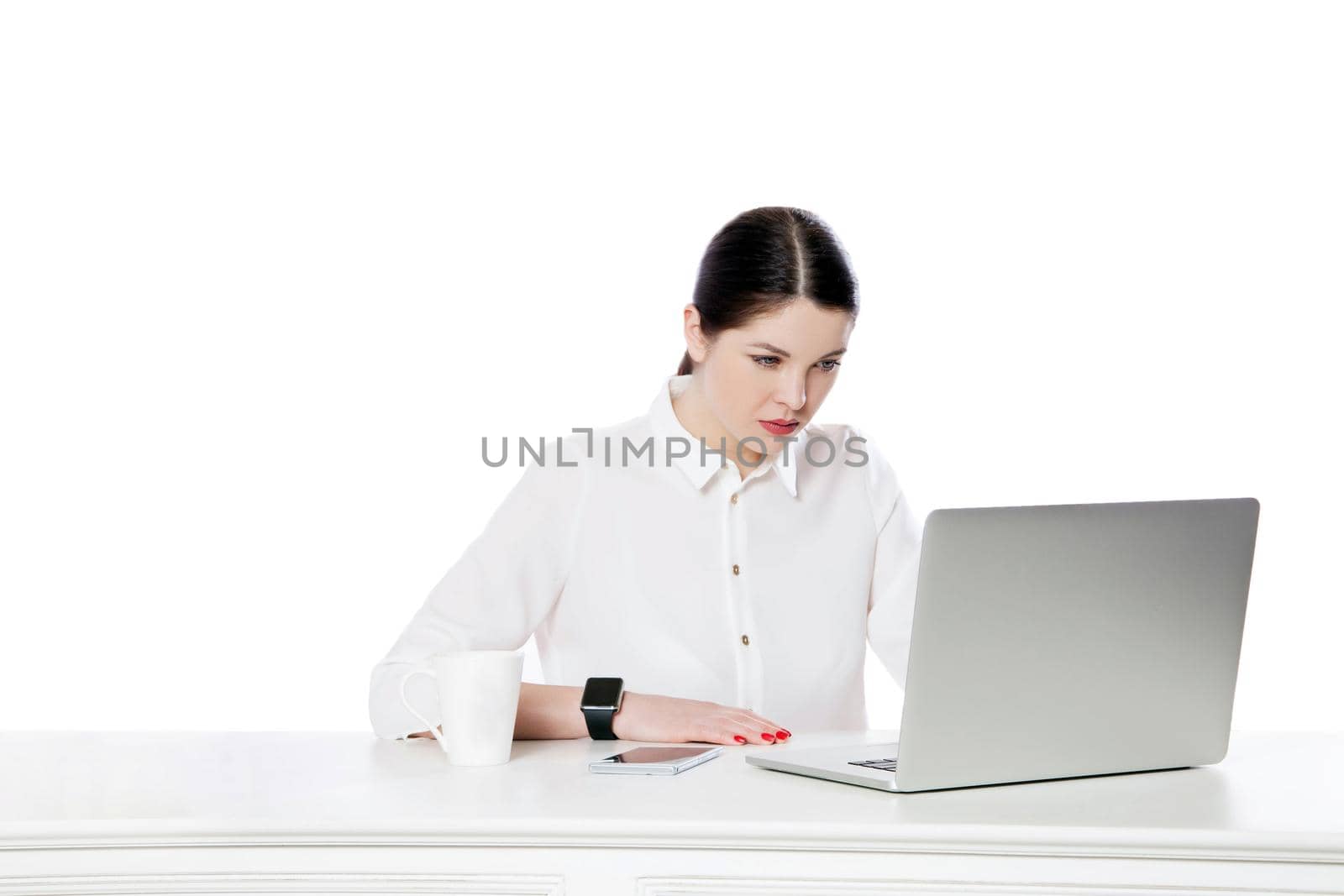 Portrait of attentive serious attractive brunette businesswoman in white shirt sitting with laptop and looking at display and reading something. by Khosro1