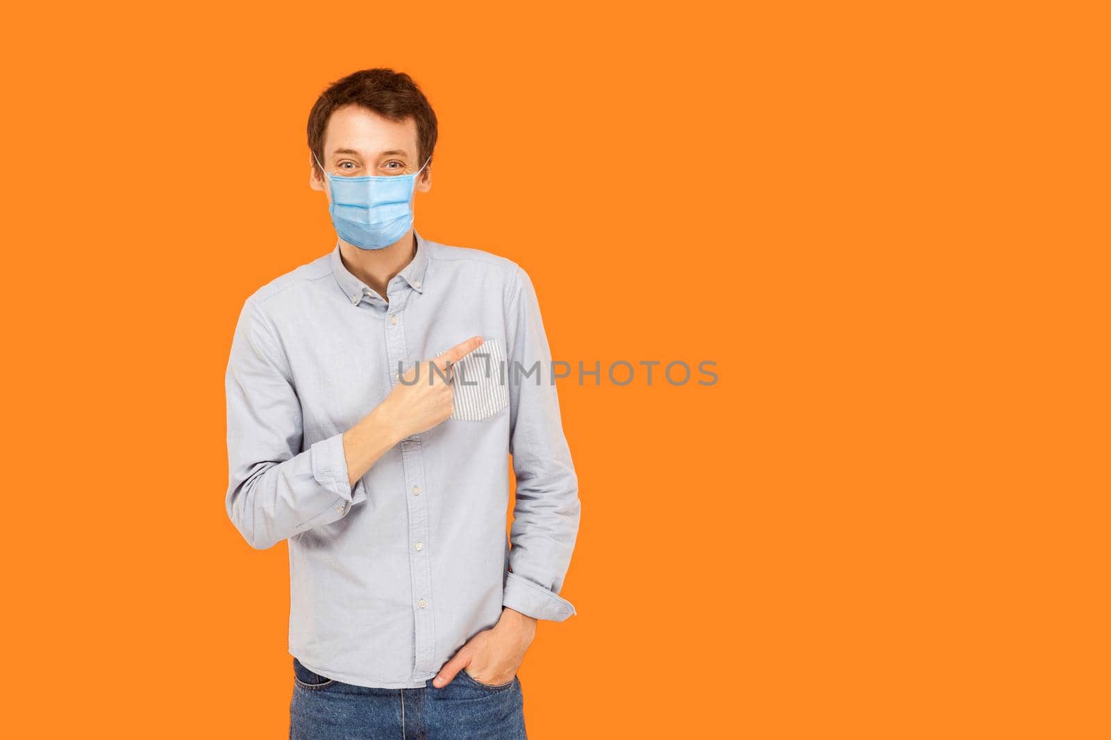 man with medical mask standing, pointing and showing background empty copy space and smiling. by Khosro1
