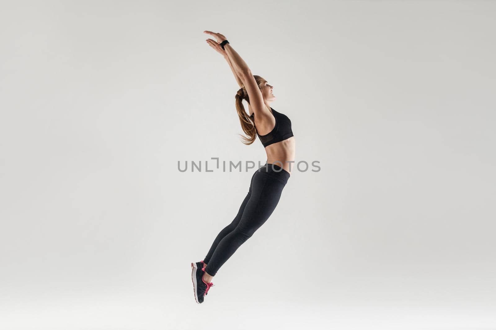 Happiness and joyful woman jumping high and hands up. Studio shot, gray background