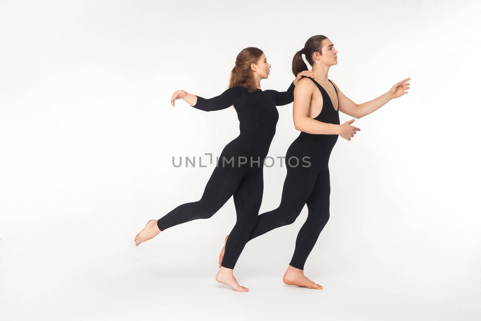 Pantomime concept. Two artist standing on toe and balancing. Studio shot, isolated on white background