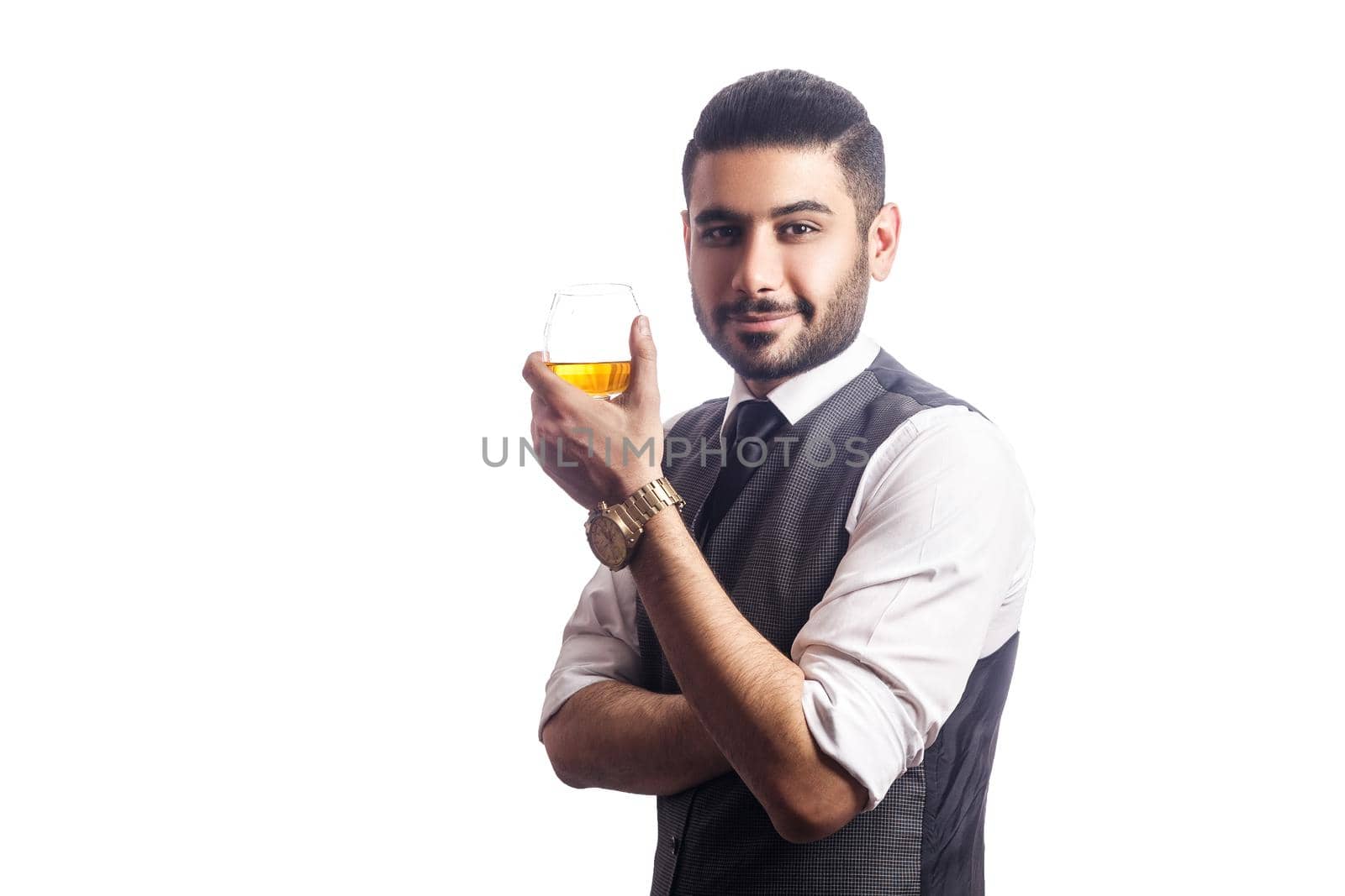 Handsome bearded businessman holding a glass of whiskey. holding glass, smiling and looking at camera. studio shot, isolated on white background.