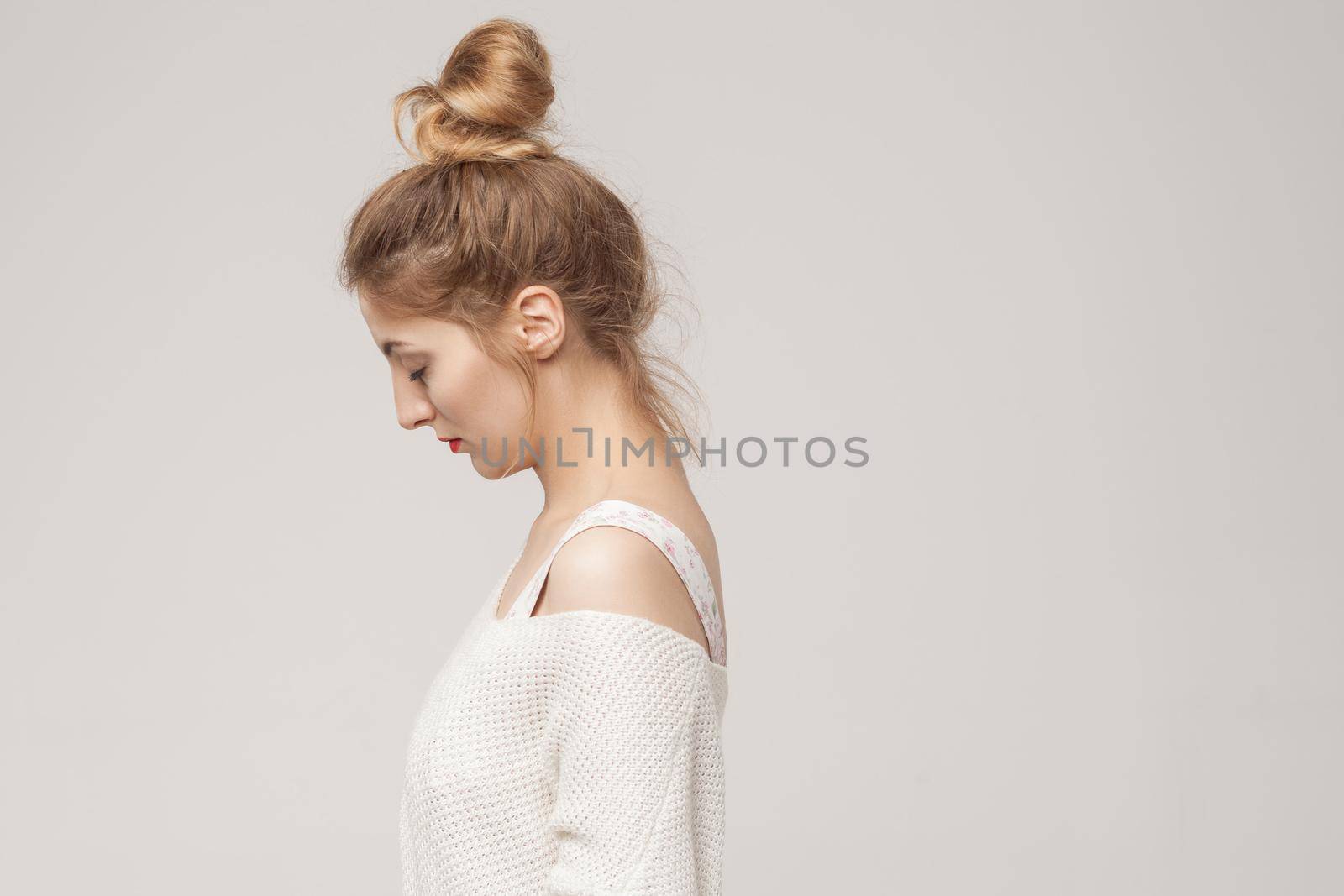 Side view young adult unwell blonde woman looking down. Studio shot