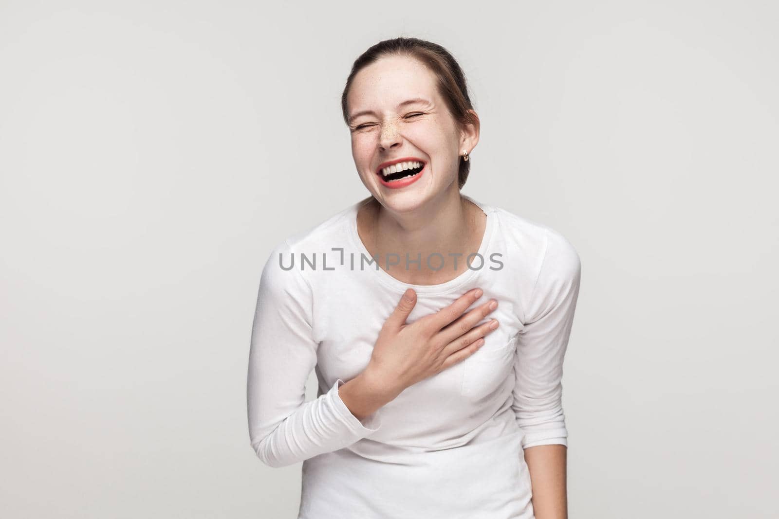 Funny concept. Expressing young adult freackles woman toothy smiling. Studio shot, isolated on gray background