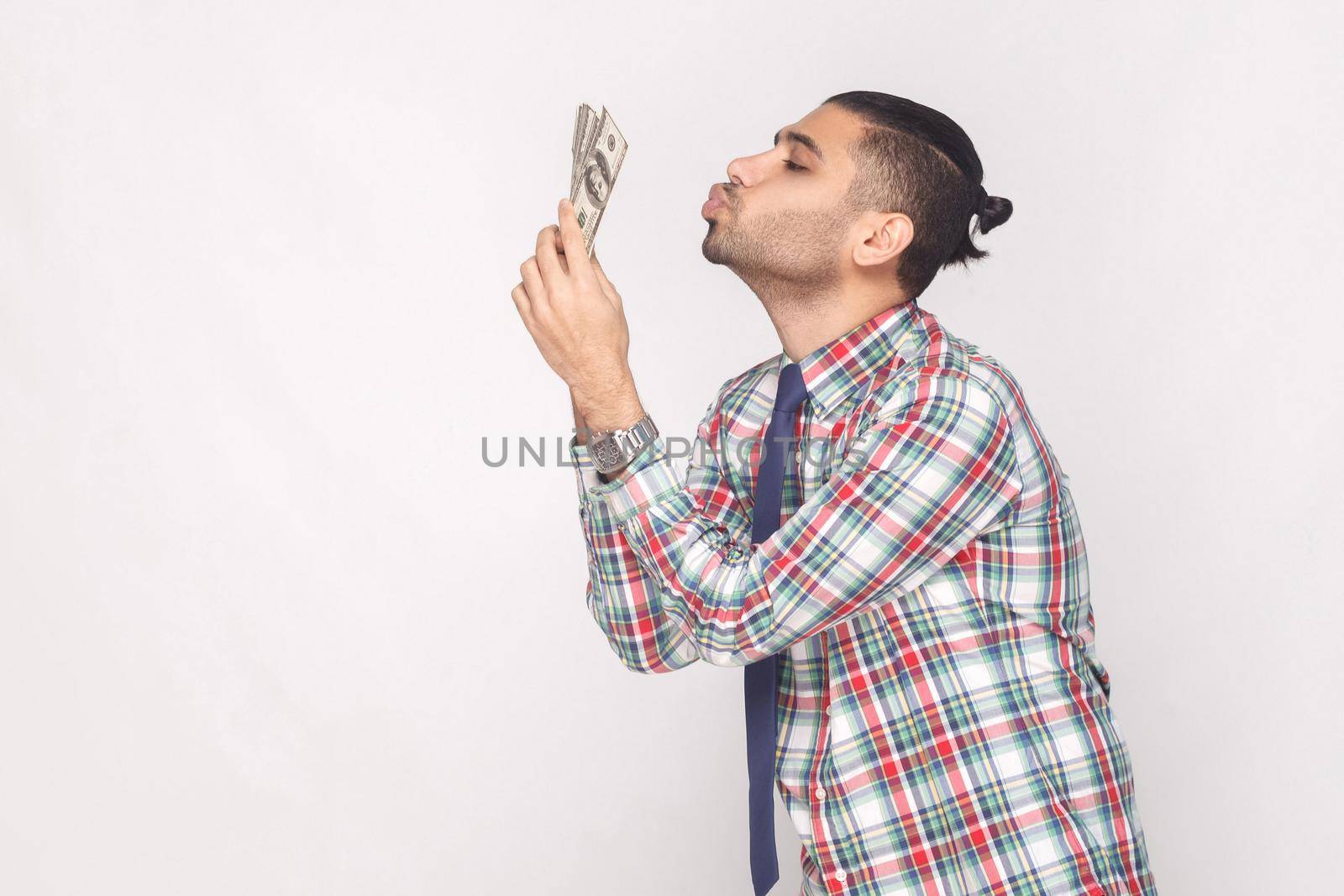 young stylish businessman in colorful checkered shirt standing and air kissing fan of dollars. by Khosro1