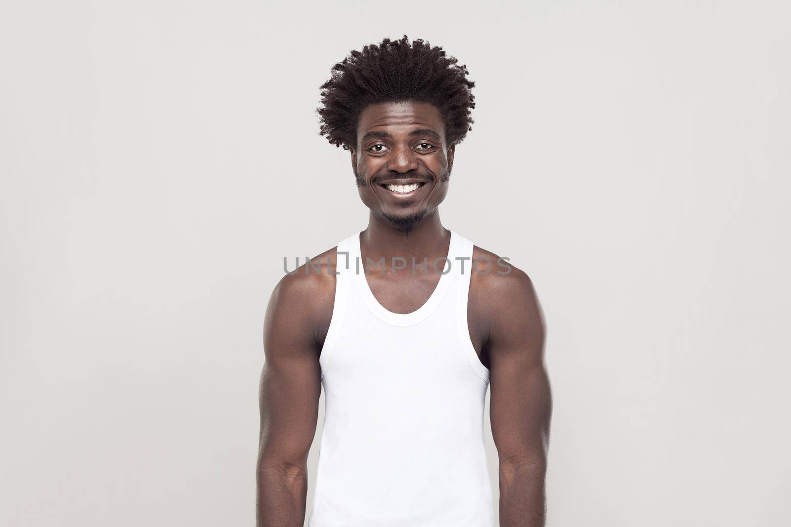 Happiness afro man looking at camera and toothy smiling. Studio shot. Gray background