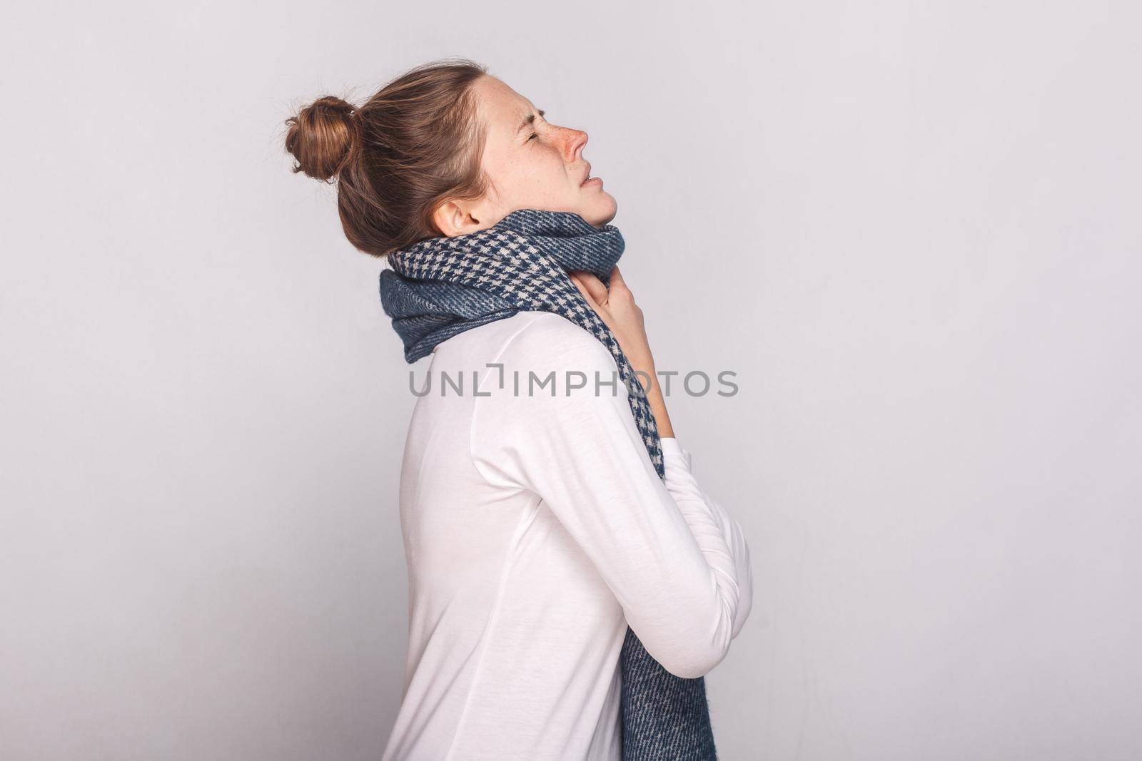 Profile view sick woman touching her neck, have cough, sore throat. Studio shot