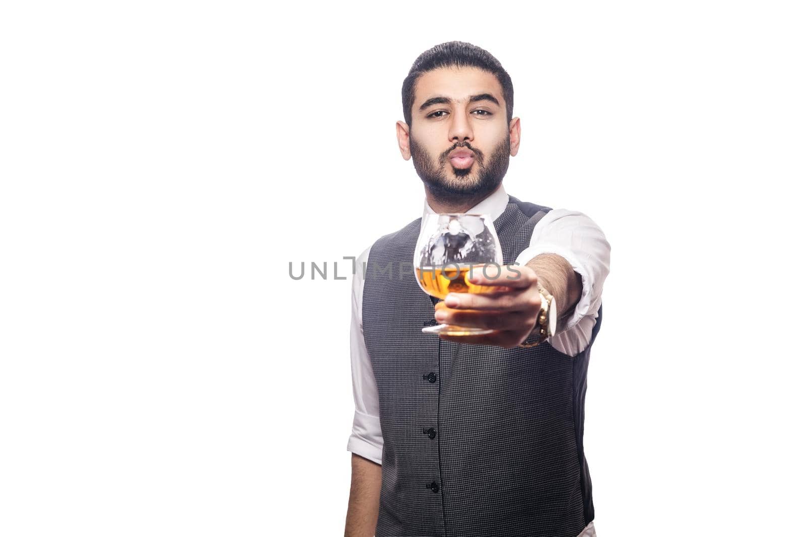 Handsome bearded businessman holding a glass of whiskey. share drink and send kiss. studio shot, isolated on white background.